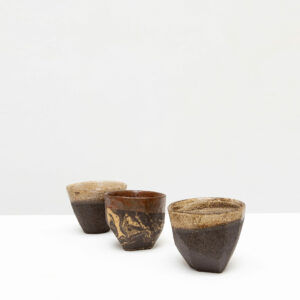 Trois tasses en céramique artisanales sur table blanche.