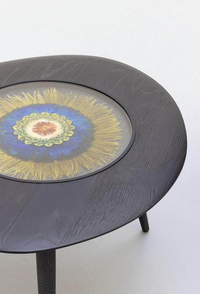 Table noire avec motif floral coloré central.