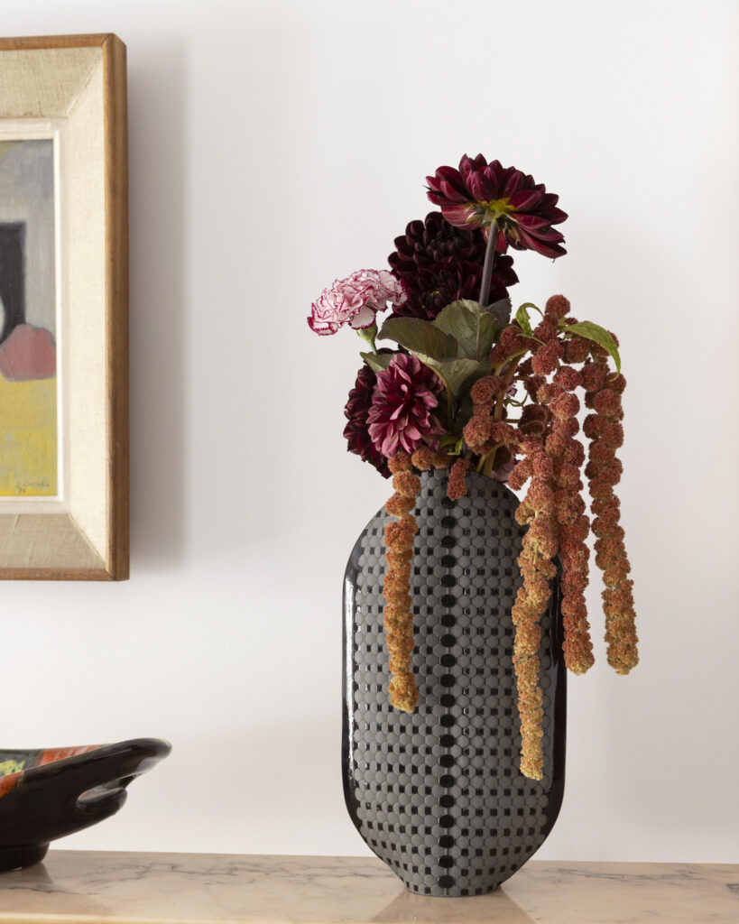 Vase moderne avec fleurs colorées sur table.